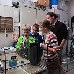 Vier Kinder und ein Erwachsener untersuchen ein Experiment mit technischem Gerät im Labor